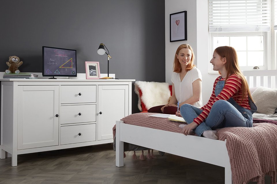 Two women watching TV in a bedroom.